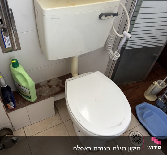 אסלה עם מיכל הדחה וכלי ניקוי בחדר אמבטיה